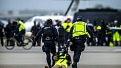 Sicherheitskräfte nehmen einen Klimaaktivisten am Flughafen Schiphol in Amsterdam fest.
