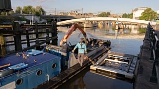 Workers from Waternet - the Amsterdam water board - emptying the catchment system of the bubble barrier at the Westerdok in Amsterdam, Netherlands.