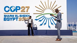 People pose for a photograph at the entrance of the COP27 UN Climate Summit, 6 November 2022