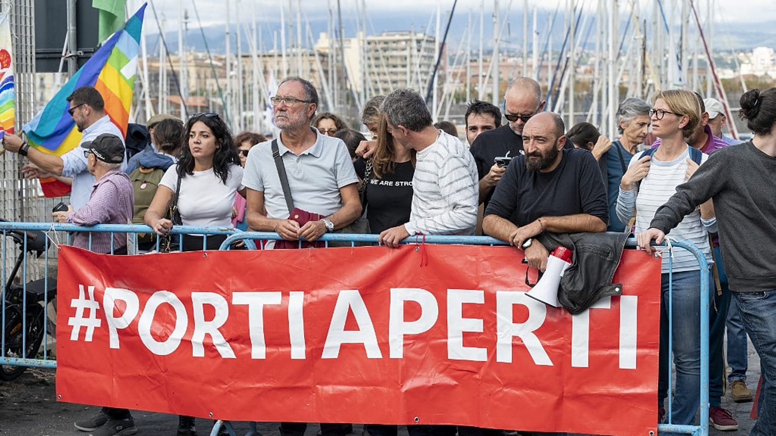Ativistas pelos direitos dos migrantes seguram faixa onde se lê "Portas Abertas", em Sicília, Itália