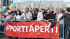 Ativistas pelos direitos dos migrantes seguram faixa onde se lê "Portas Abertas", em Sicília, Itália