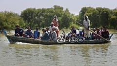 Villagers with their belongings cross a flooded area on a boat, in Dadu, a district of southern Sindh province, Pakistan, Sept. 23, 2022.
