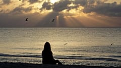 Sahilde meditasyon yapan bir kadın