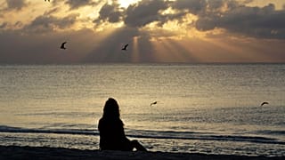 Sahilde meditasyon yapan bir kadın