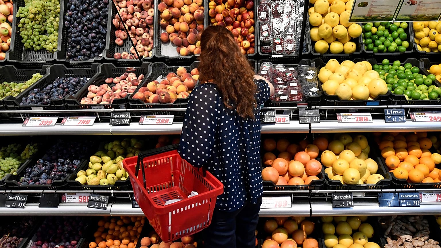 Vásárló válogat a gyümölcsök közül egy üzletben