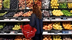 Vásárló válogat a gyümölcsök közül egy üzletben