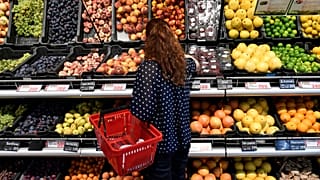 Vásárló válogat a gyümölcsök közül egy üzletben