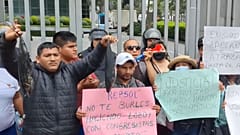 Pescadores protestan con peces muertos tintados de negro frente a la sede de Repsol en Lima.