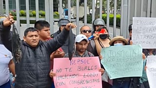 Pescadores protestan con peces muertos tintados de negro frente a la sede de Repsol en Lima.
