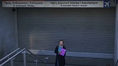 Una mujer espera frente a una entrada de metro cerrada por la huelga en Atenas, Grecia. 