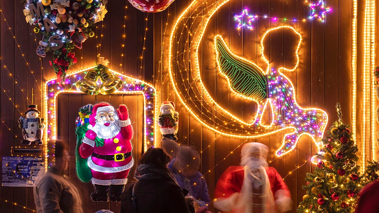 Menschen stehen vor dem weihnachtlich geschmückten Haus 
