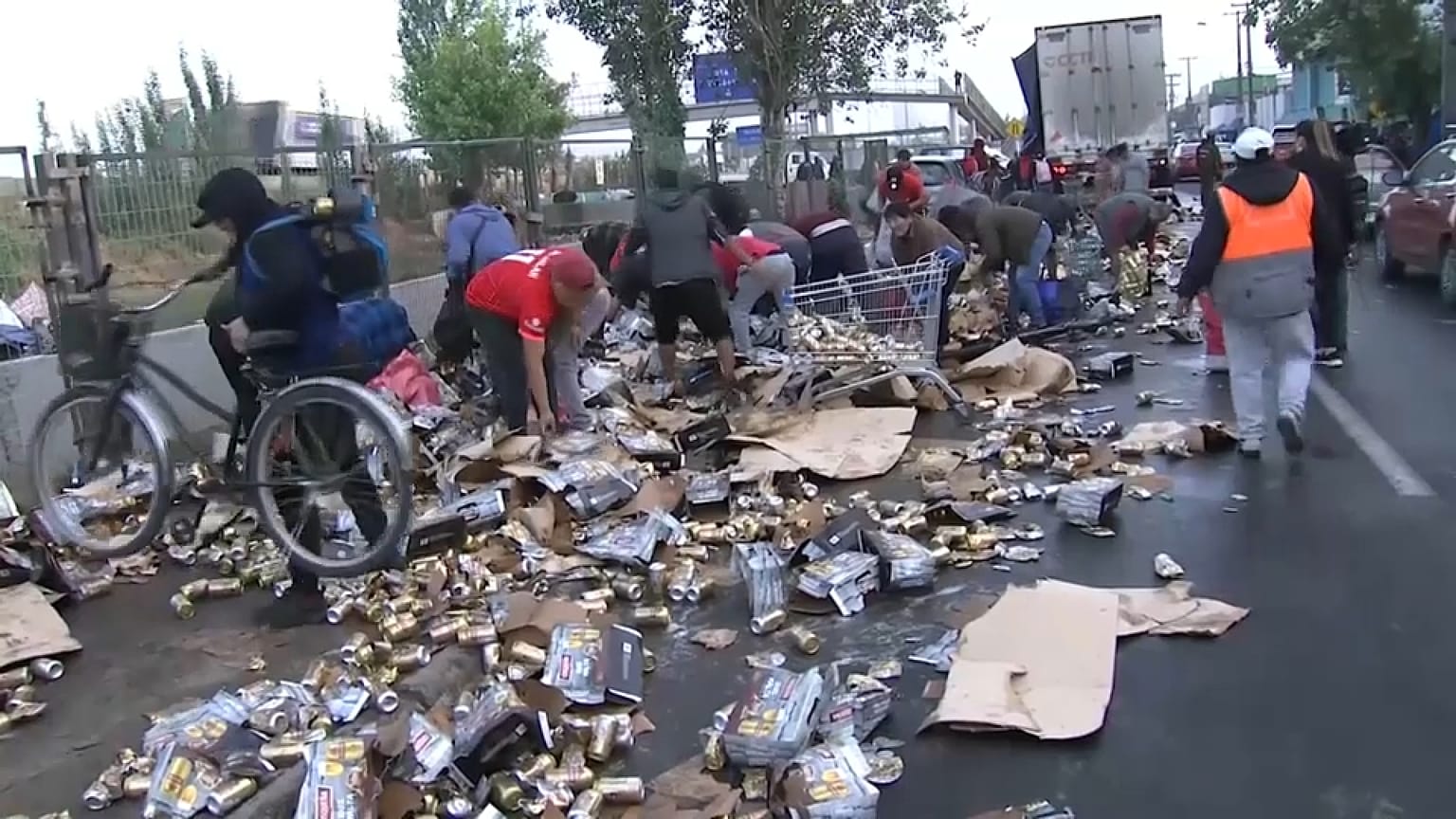 Los transeúntes recogiendo las latas de cerveza derramadas por el camión