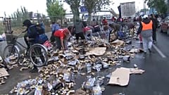 Los transeúntes recogiendo las latas de cerveza derramadas por el camión