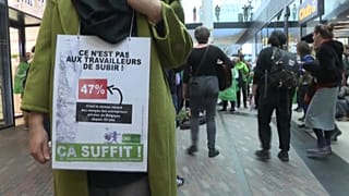 Woman with a sign saying "it is not for the workers to suffer" during protest in a Brussels shopping centre. 