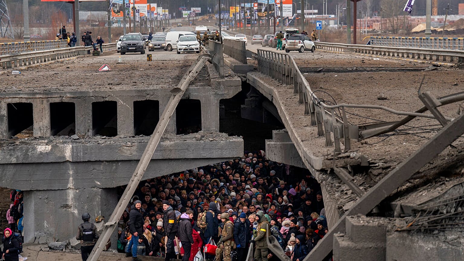 Des Ukrainiens se massent sous un pont détruit alors qu'ils tentent Irpin, en Ukraine, samedi 5 mars 2022.
