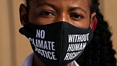 A woman wears a face mask that reads "no climate justice without human rights" during a silent protest for climate justice and human rights at COP27.
