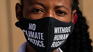 A woman wears a face mask that reads "no climate justice without human rights" during a silent protest for climate justice and human rights at COP27.