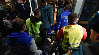 Volunteers and paramedics carry an elderly evacuee from Kherson into a hall on Nov. 10th 2022