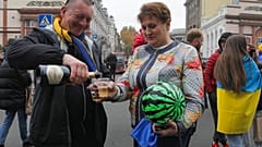 Eine Frau mit einer Wassermelone in der Hand und ein Mann feiern in der ukrainischen Stadt Odessa die Befreiung Chersons