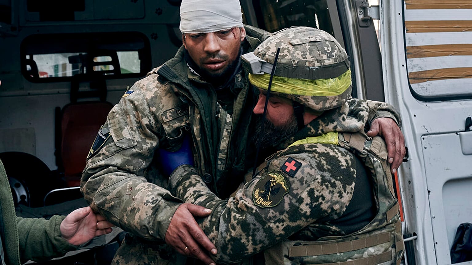 A Ukrainian soldier helps a wounded soldier at a hospital in Bakhmut, Donetsk region, Ukraine, Wednesday, Nov. 9, 2022.