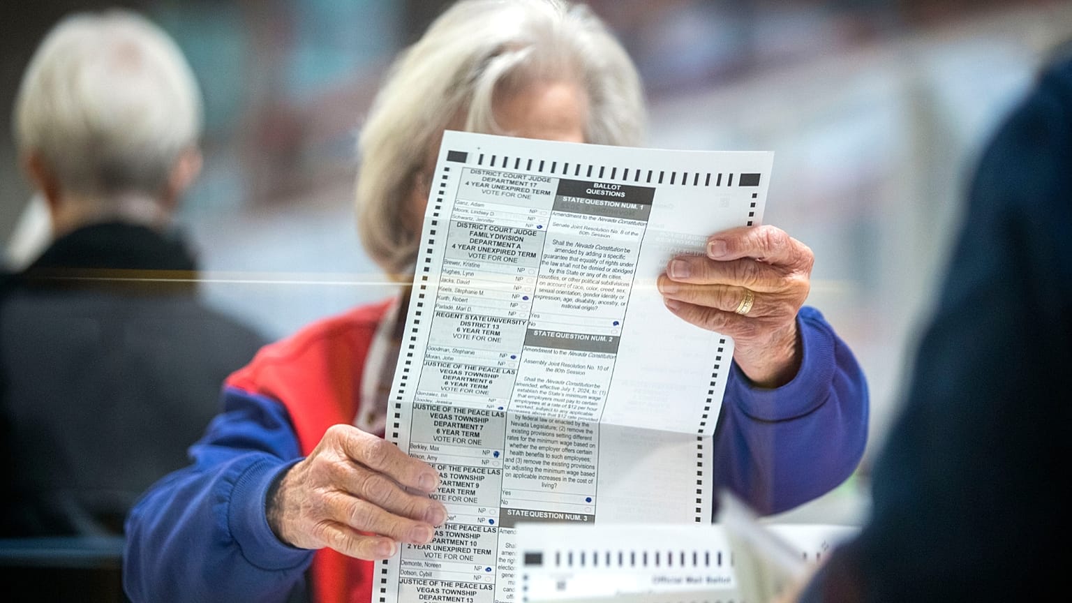 An election worker inspects a mail-in ballot in the count room at the Clark County Election Department in North Las Vegas, Saturday, Nov. 12, 2022.