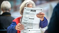 An election worker inspects a mail-in ballot in the count room at the Clark County Election Department in North Las Vegas, Saturday, Nov. 12, 2022.