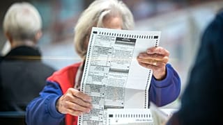 An election worker inspects a mail-in ballot in the count room at the Clark County Election Department in North Las Vegas, Saturday, Nov. 12, 2022.