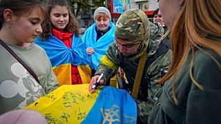 Un soldat ukrainien dédicace un drapeau