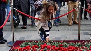 A woman leaves a flower at a memorial at the scene of Sunday's explosion on Istanbul's popular pedestrian Istiklal Avenue in Istanbul, Monday, Nov. 14, 2022.