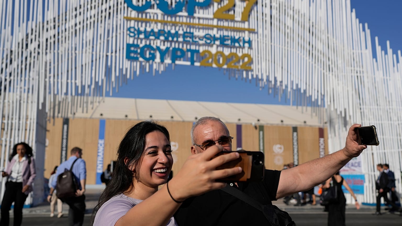 Two people take selfies at the COP27 UN Climate Summit.