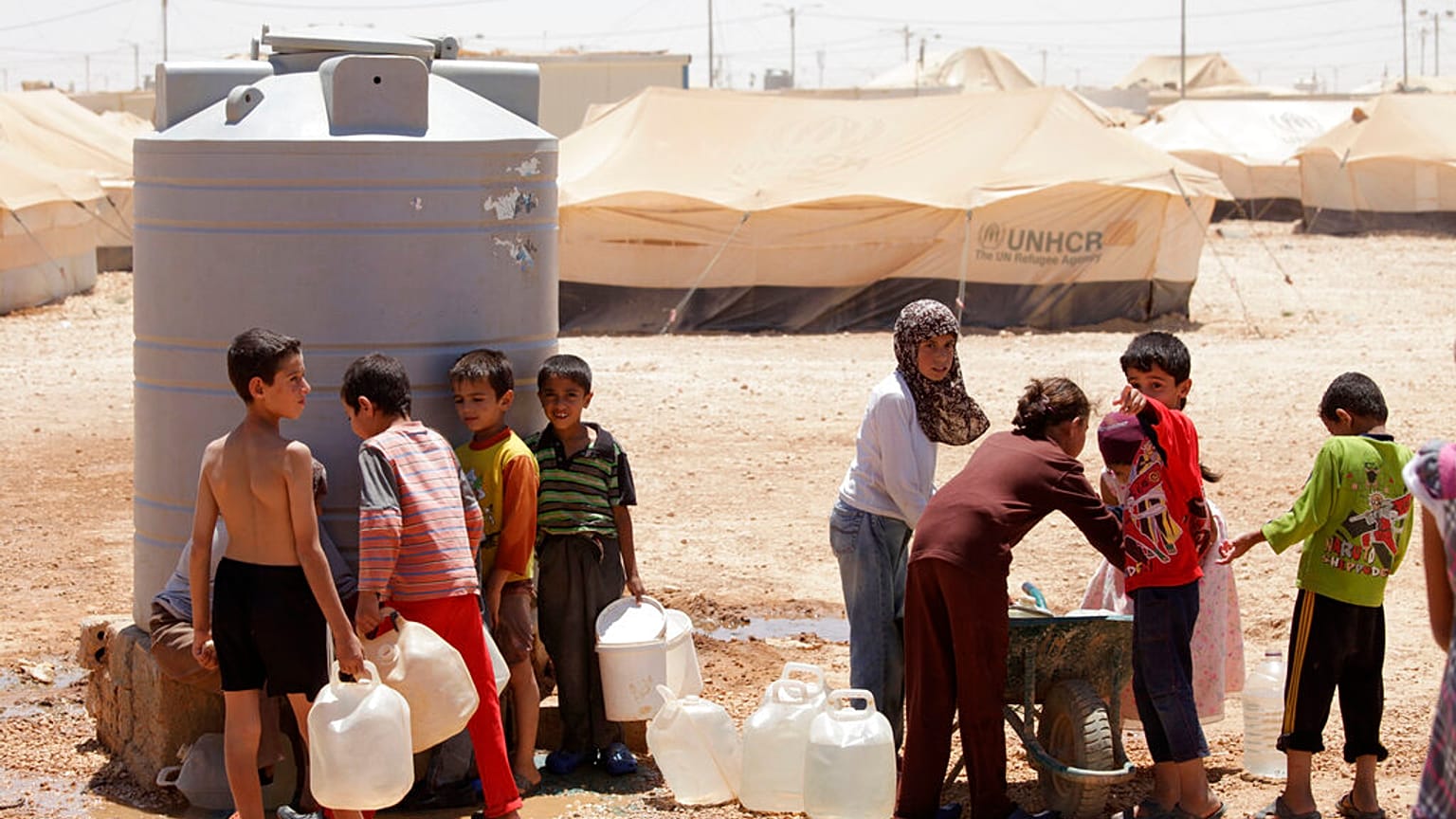 Fiatal szíriai menekültek töltik meg víztartályaikat a zaatari menekülttáborban, Jordániában, 2013-ban