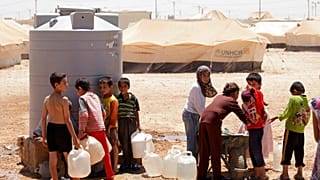 Fiatal szíriai menekültek töltik meg víztartályaikat a zaatari menekülttáborban, Jordániában, 2013-ban