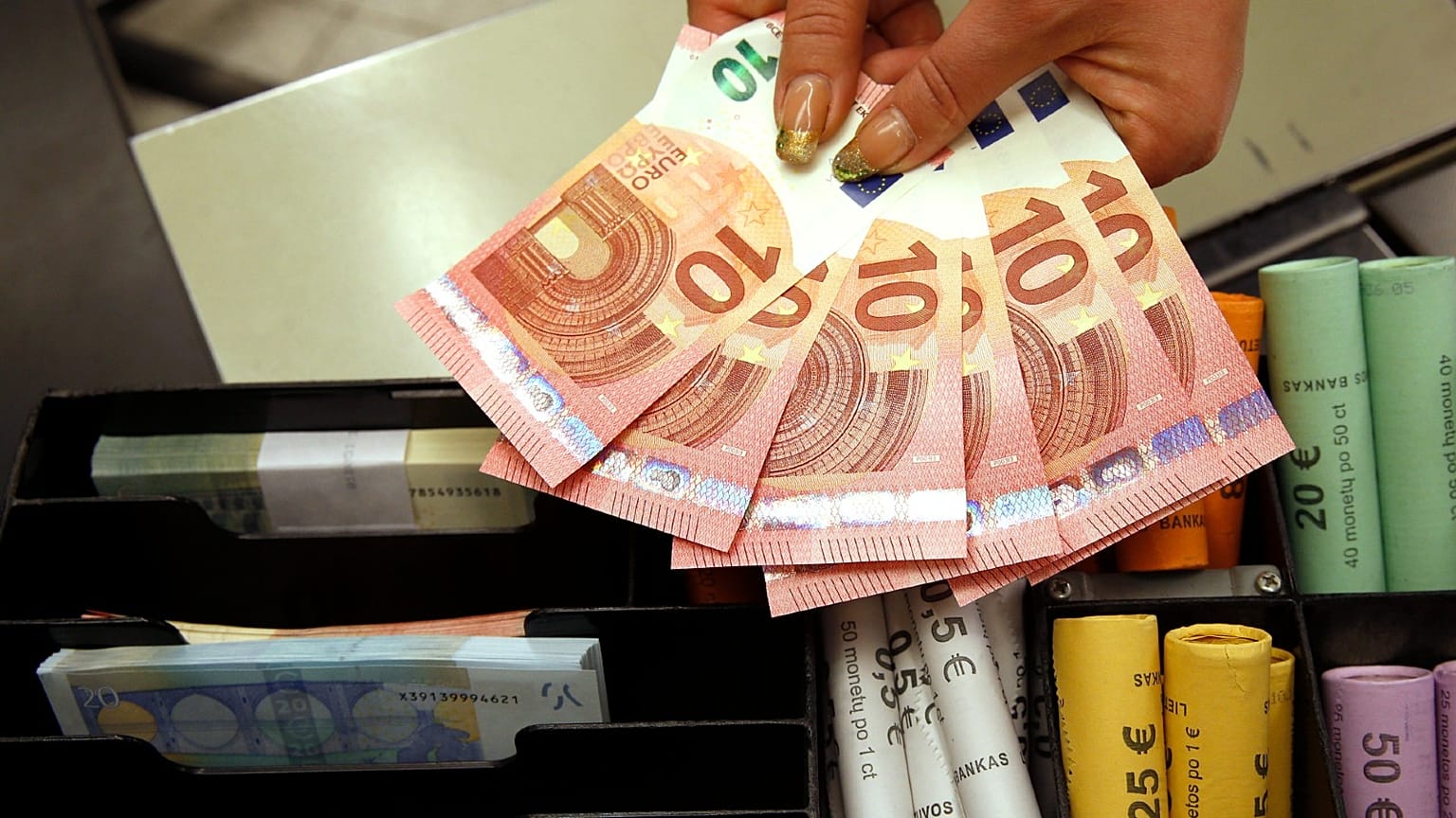 Euro coins and banknotes are shown by a salesclerk at a shop in Vilnius, Lithuania.