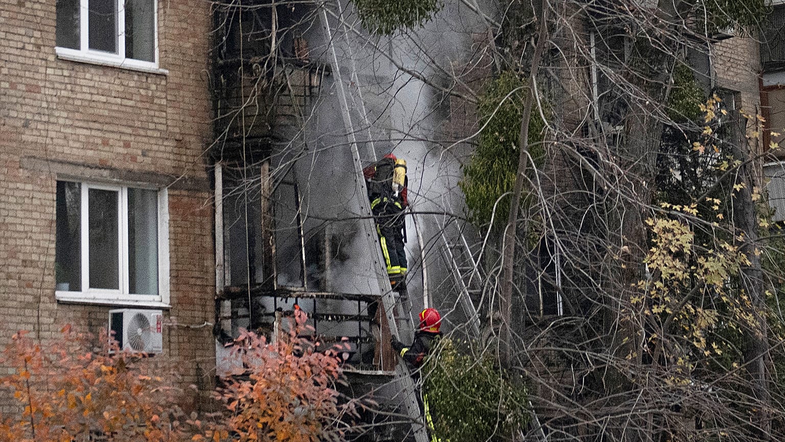 Ukrainian State Emergency Service firefighters work to extinguish a fire at the scene of a Russian shelling in Kyiv, 15 November 2022