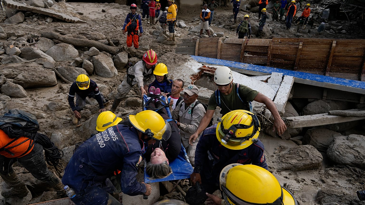 Trabajadores de emergencia llevan a una mujer rescatada de una zona inundada por un río que se desbordó. El 18 de octubre de 2022.