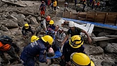 Trabajadores de emergencia llevan a una mujer rescatada de una zona inundada por un río que se desbordó. El 18 de octubre de 2022.