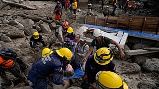 Trabajadores de emergencia llevan a una mujer rescatada de una zona inundada por un río que se desbordó. El 18 de octubre de 2022.
