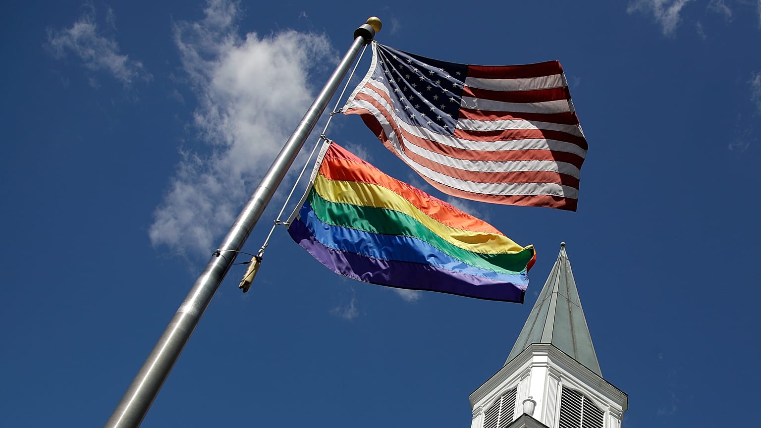 A gay pride rainbow flag flies with the U.S. flag in front of the Asbury United Methodist Church in Prairie Village, Kansas, on Friday, April 19, 2019.