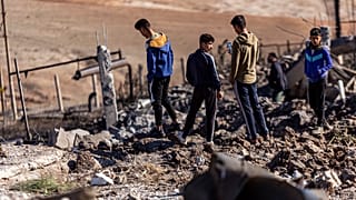 People inspect a site damaged by Turkish airstrikes that hit an electricity station in the village of Taql Baql, Syria.