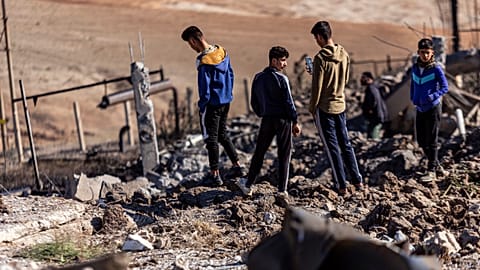 People inspect a site damaged by Turkish airstrikes that hit an electricity station in the village of Taql Baql, Syria.