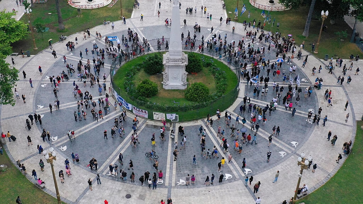 Personas y miembros de las agrupaciones de Madres de Plaza de Mayo de derechos humanos y H.I.J.O.S pasan por delante de la Pirámide de Mayo en Buenos Aires, Argentina
