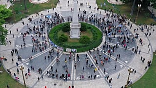 Personas y miembros de las agrupaciones de Madres de Plaza de Mayo de derechos humanos y H.I.J.O.S pasan por delante de la Pirámide de Mayo en Buenos Aires, Argentina