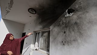 امرأة فلسطينية تشير إلى ثقوب على جدار ناجمة عن اقتحام الجيش الإسرائيلي للمنزل