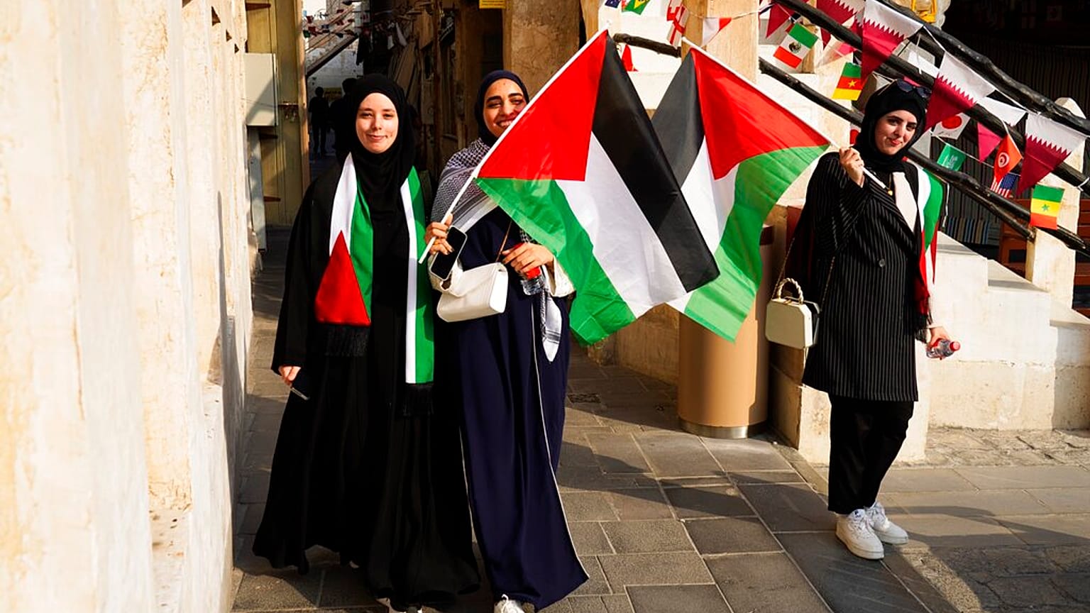 نساء فلسطينيات يلوحن بالعلم الفلسطيني قبل انطلاق كأس العالم لكرة القدم في الدوحة، قطر، السبت 19 نوفمبر 2022