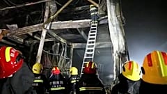 Rescuers use a ladder to climb into the remains of a fire at an industrial wholesaler in Anyang in central China's Henan province, 21 November 2022