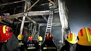 Rescuers use a ladder to climb into the remains of a fire at an industrial wholesaler in Anyang in central China's Henan province, 21 November 2022