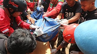 Rescuers remove the body of a victim recovered from under the rubble at a village hit by a landslide in Cianjur, West Java