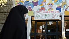 امرأة محجبة تمر من أمام لافتة لدعم الأسر الأفغانية" في مدرسة سانت أرميل في رين، غرب فرنسا، في 7 سبتمبر 2021.