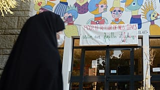 امرأة محجبة تمر من أمام لافتة لدعم الأسر الأفغانية" في مدرسة سانت أرميل في رين، غرب فرنسا، في 7 سبتمبر 2021.