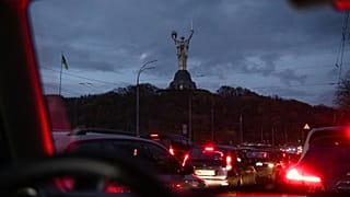 Cars move in the dark, with the Motherland Monument in the background, during a blackout in Kyiv, Ukraine, Friday, Nov. 11, 2022
